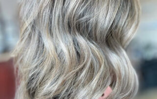 A woman showing off her recent gray blending haircut & style at Jenny's Salon